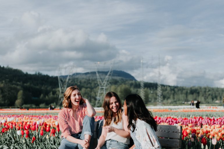 Friends sitting in tulips and laughing