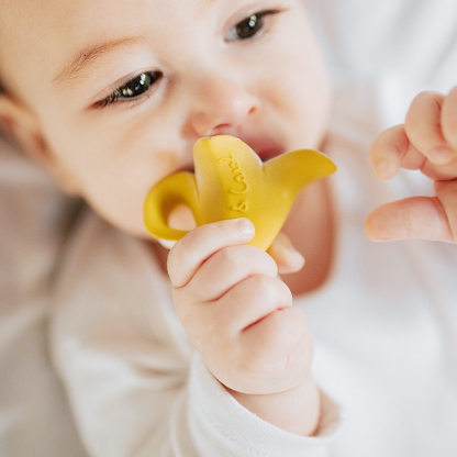 Baby with teething toy shaped like a banana