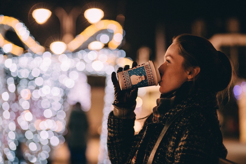 woman sipping drink at christmas market