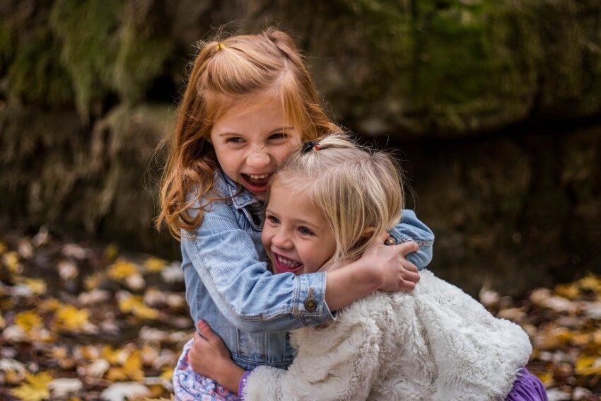 Two young children laugh and hug each other.